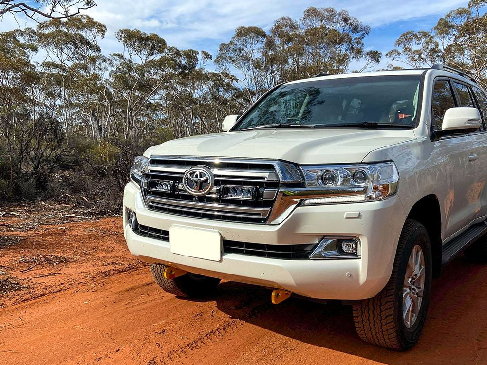 White Toyota SUV on a dirt road with trees in the background