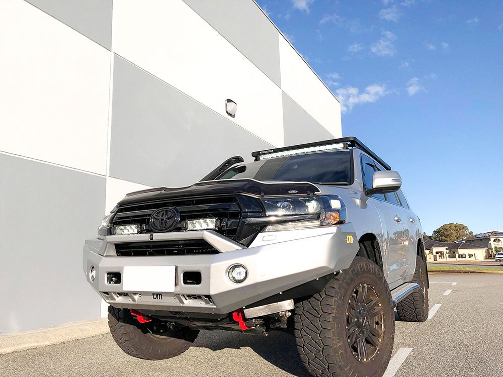 Toyota SUV with off-road modifications parked on a road with a building and blue sky in the background with Lazer Lamps Grille Kit – Toyota Land Cruiser 200 Series (2015–2021)