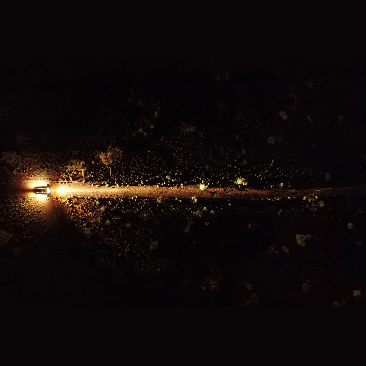 Aerial night shot showing the beam of a pair of Lightforce BEAST driving lights throwing down a dirt track