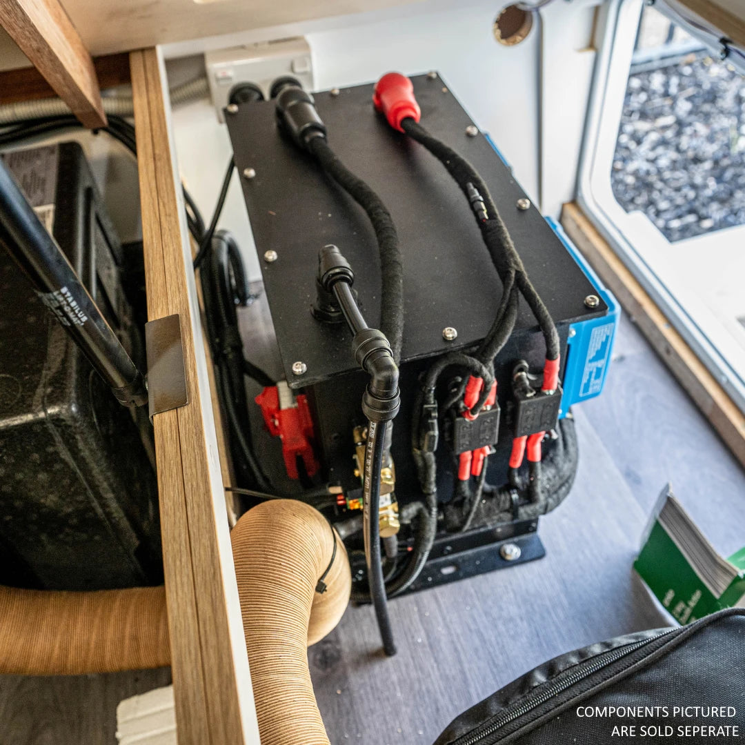 The lithium battery compartment installed against a wall in a fitted-out vehicle, seen from above, with heavy battery cable, in-line fuse holders and the vent line running off the top