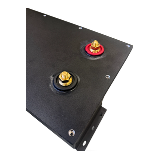 Close-up of the compartment lid showing the red positive and black negative terminal studs, each brass stud sealed through the plate with a rubber grommet – Lithium Battery Compartment