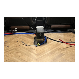 Car interior with wiring and a diesel heater on a wooden floor.