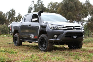 Gray Toyota truck parked in a grassy field with trees in the background – SAFARI ARMAX SNORKEL Hilux Wide Body 2015 onwards (Not compatible with Factory flares on 2015-2020 models) (some models require flare kit)