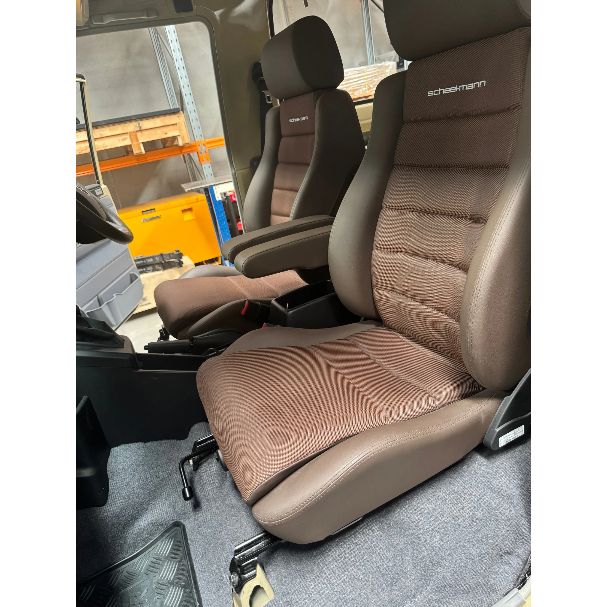 Beige car seat with visible Scheelmann branding in a workshop setting