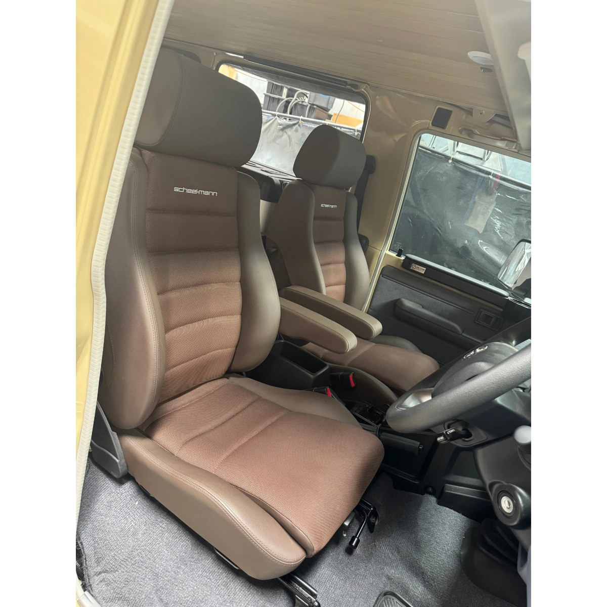 Interior of a vehicle with brown seats and visible branding – Scheelmann Traveller Seat with Armrest