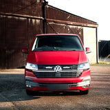 Red Volkswagen van parked in front of a rustic building.