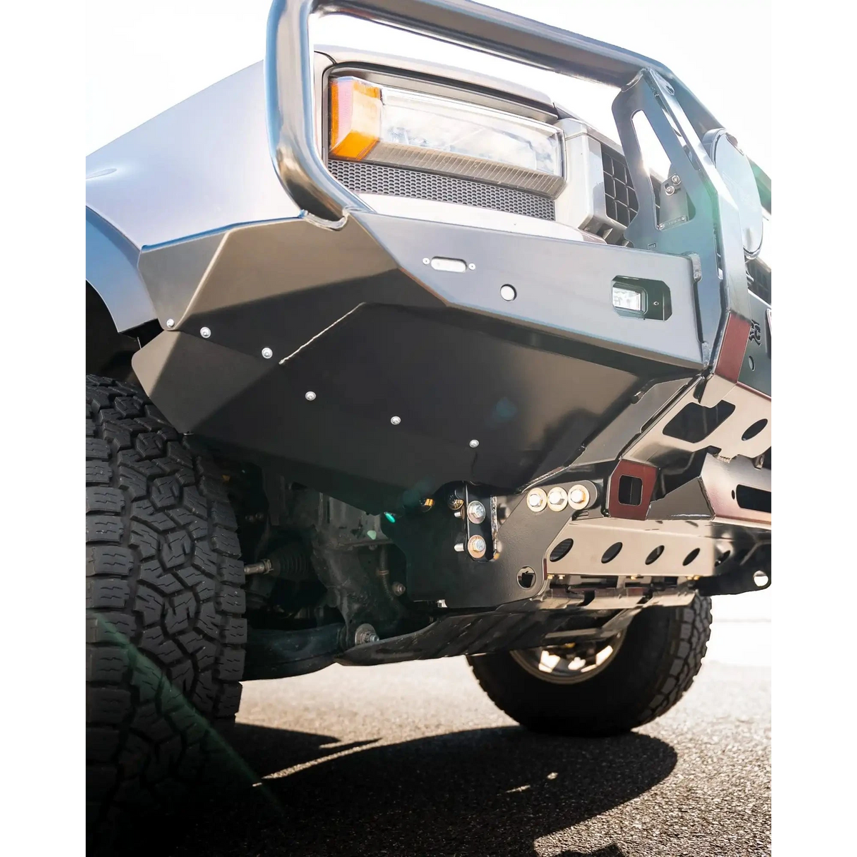 Close-up of a vehicle's front bumper and tire on a road – TCC 250 Prado Bull Bar