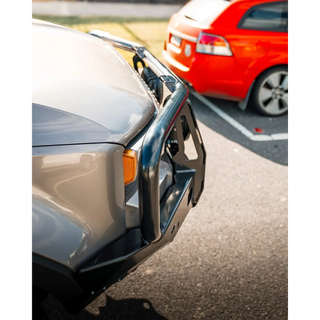 Close-up of a car bumper with another car partially visible in the background – TCC 250 Prado Bull Bar