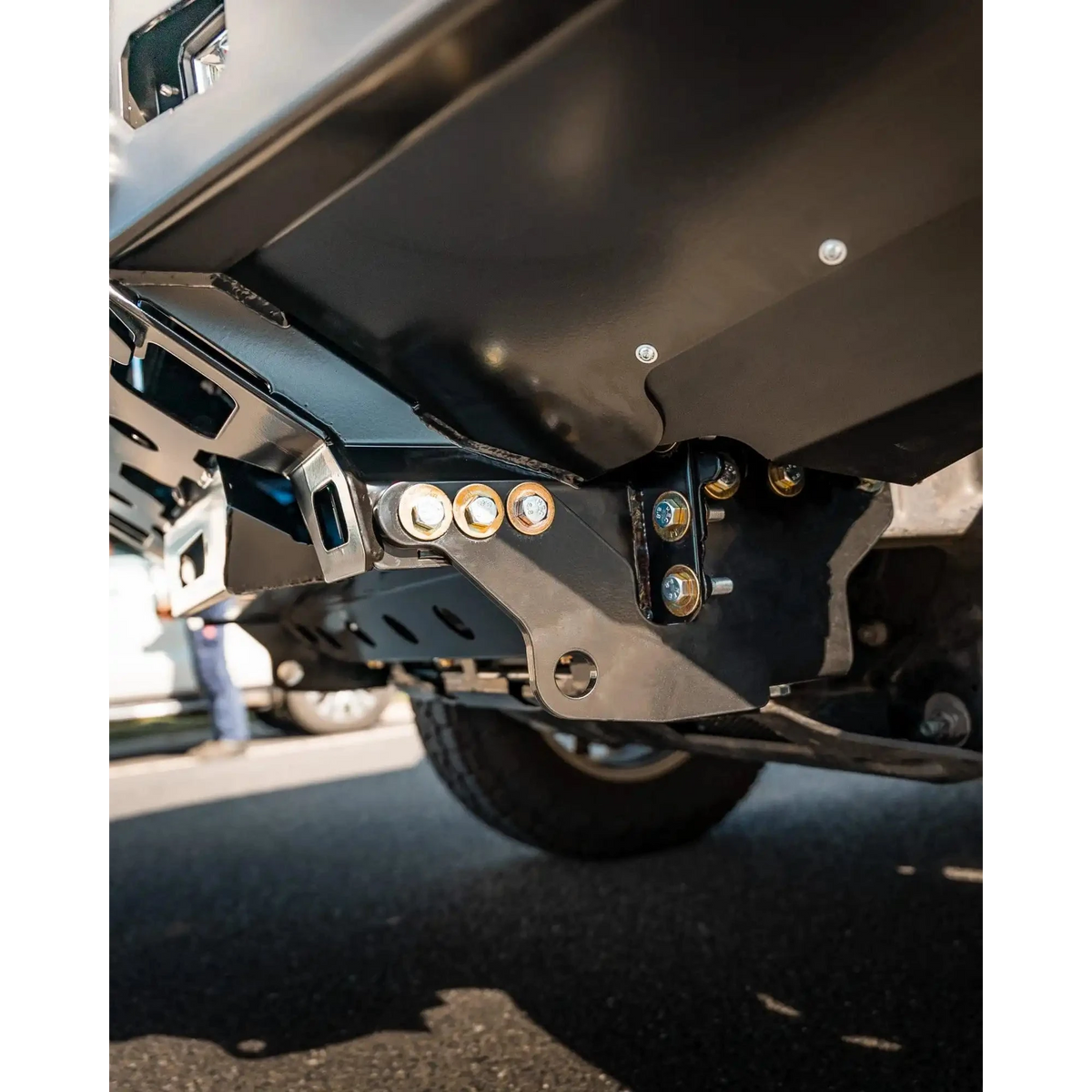 Close-up of a vehicle's undercarriage with visible suspension components on a road – TCC 250 Prado Bull Bar