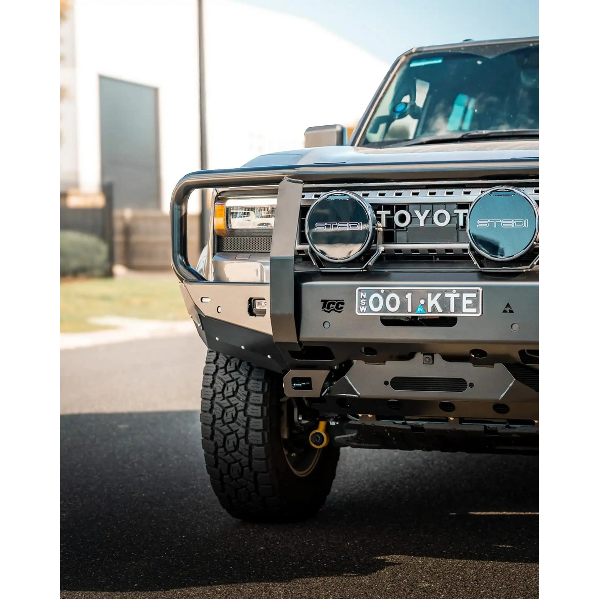 Front view of a Toyota vehicle with a grille guard on a road – TCC 250 Prado Bull Bar