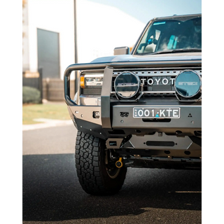 Front view of a Toyota vehicle with a grille guard on a road – TCC 250 Prado Bull Bar