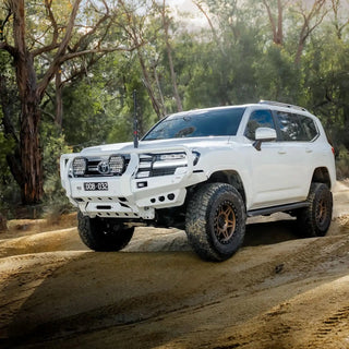White Toyota SUV driving on a dirt road in a forested area – TCC Toyota LandCruiser 300 Series Bull Bar