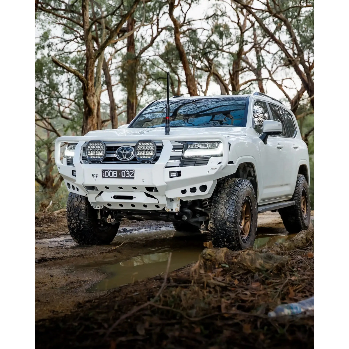White Toyota SUV driving through a forest on a muddy path – TCC Toyota LandCruiser 300 Series Bull Bar