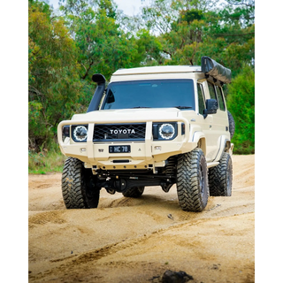 Toyota off-road vehicle on a dirt road with trees in the background – TCC 70 Series Bull Bar - Facelift (2024 - Present)