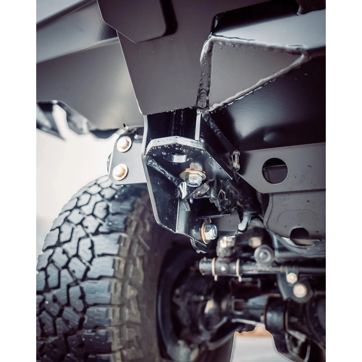 Close-up of a vehicle's suspension system with tire and undercarriage details – TCC 70 Series Single Cab Bull Bar - Facelift (2024 - Present)