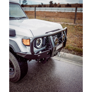 White off-road vehicle on a road with a rural landscape in the background – TCC 70 Series Single Cab Bull Bar - Facelift (2024 - Present)