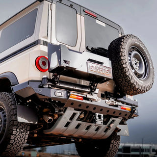 TCC INEOS Grenadier Rear Bar – beige Grenadier with the spare tyre mounted, against a clear sky