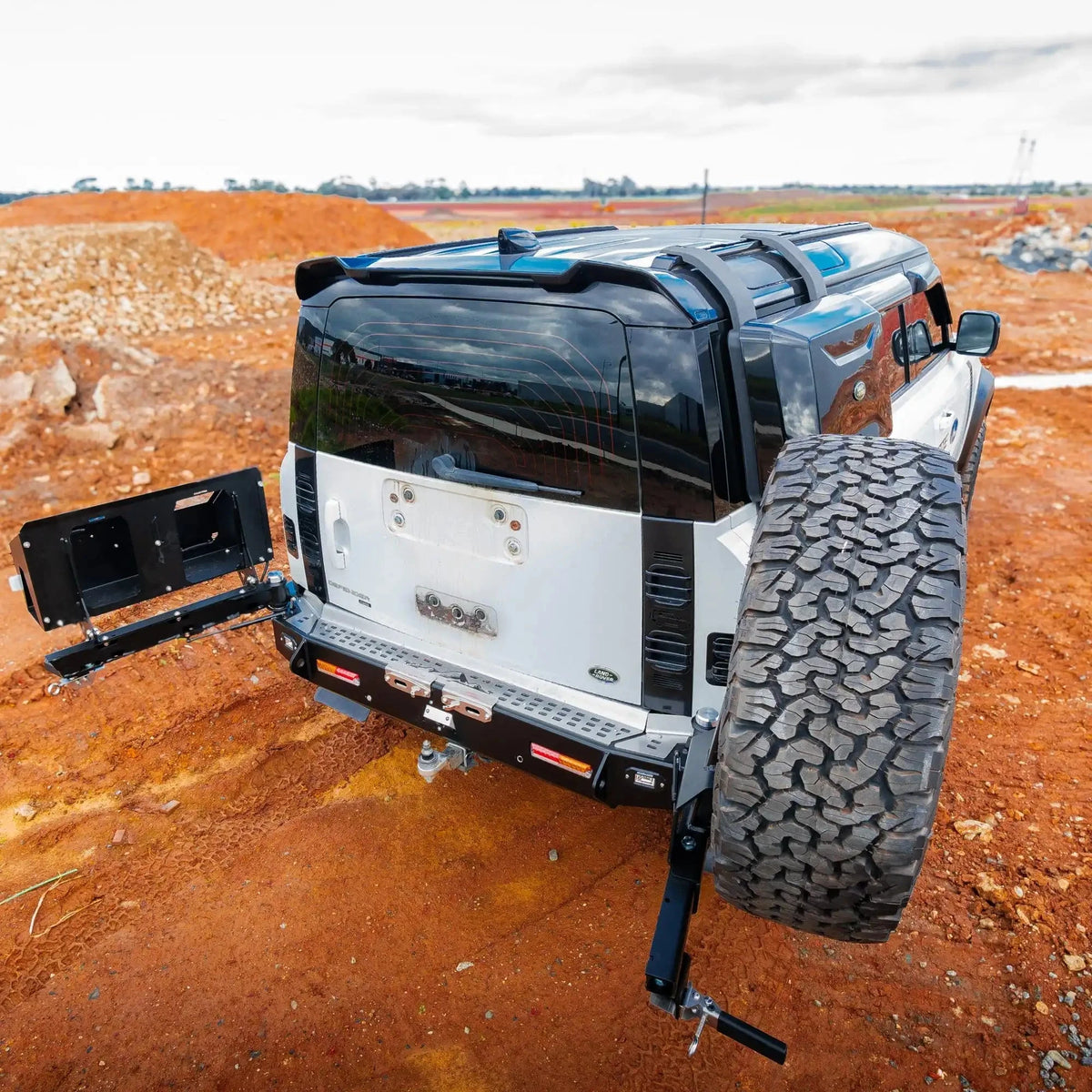 Black and white off-road vehicle with large tire on a dirt field – TCC Land Rover Defender 2020+ Rear Bar
