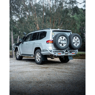 Silver SUV with spare tires on a gravel road surrounded by trees – TCC Toyota LC300 Series Rear Bar