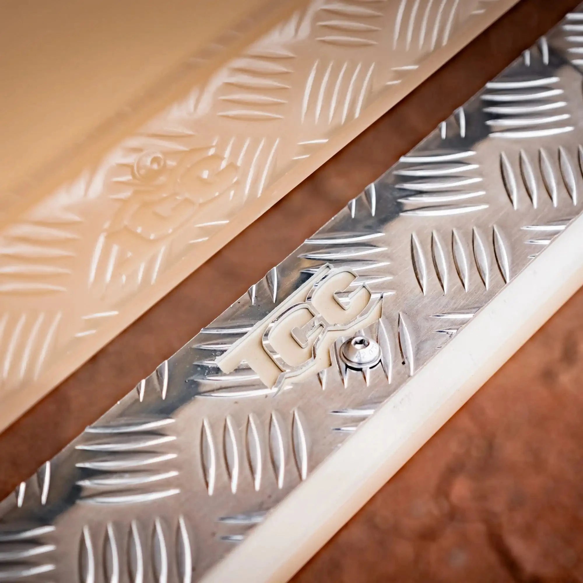 Metallic surface with a textured pattern and 'TCC' branding – TCC Toyota LC78 Troopcarrier Side Steps