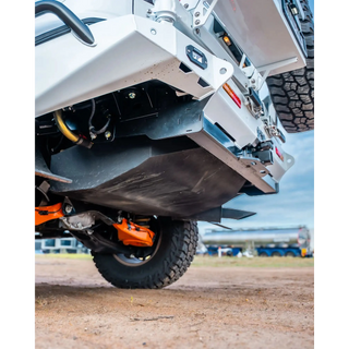 Close-up of a vehicle's undercarriage with visible suspension and tires on a dirt surface – TCC Y62 Patrol Rear Bar