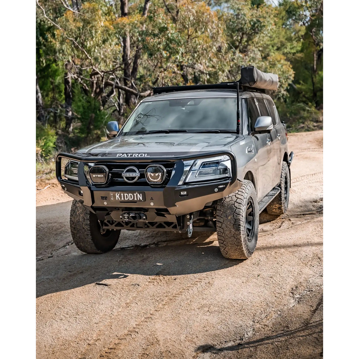Nissan Patrol SUV on a dirt road with trees in the background – TCC Y62 Patrol S5 Bull Bar