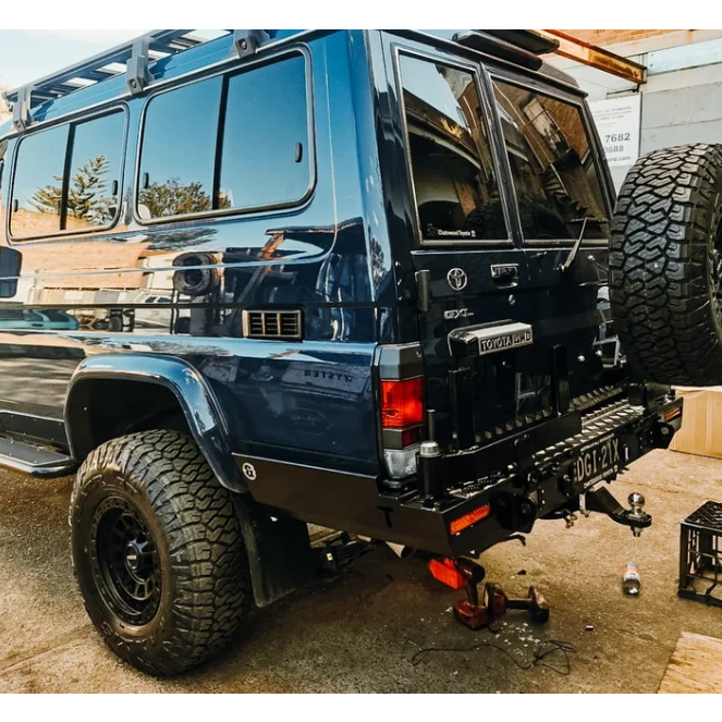 Blue off-road vehicle with large tires and Thorburns LC75/78 Rear Bar on a concrete surface.