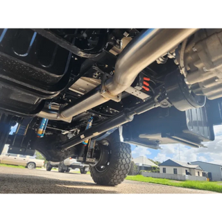 Close-up of a vehicle's undercarriage with visible suspension components on a road – Torqit 4″ EXHAUST BRAKE Back Performance EXHAUST for Isuzu NPS Truck
