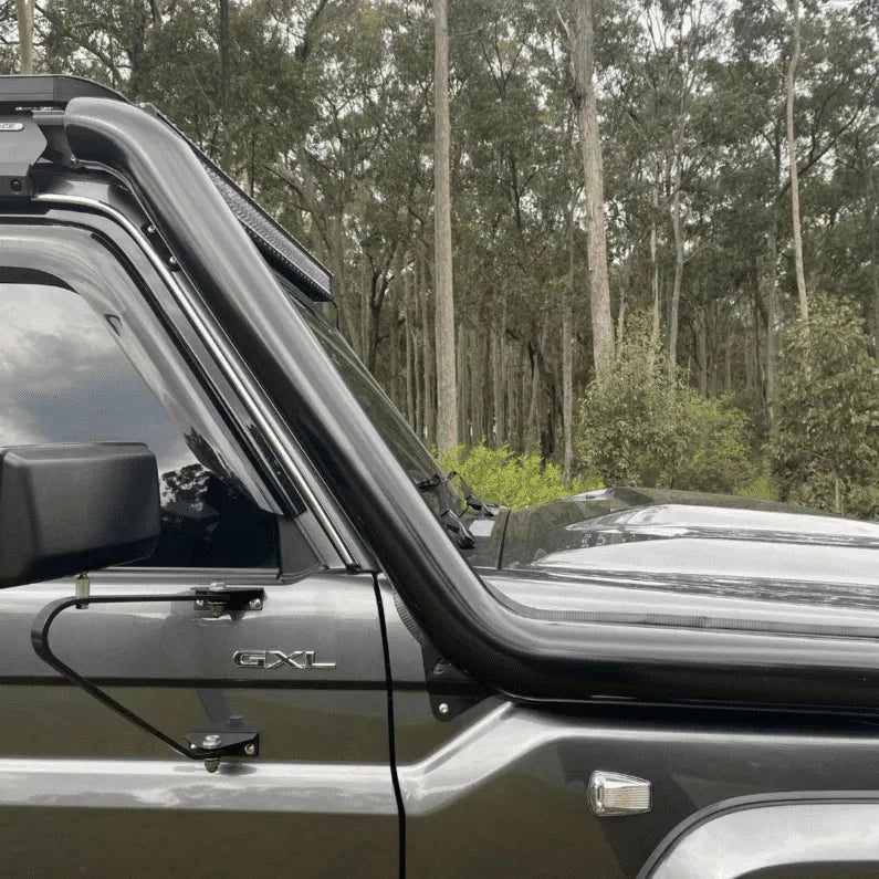 Side view of a 79 Series Landcruiser with snorkel and roof rack in a forest setting – Torqit 4" Stainless Steel Snorkel (Matte Black) for Toyota 79 Series Landcruiser