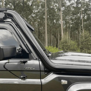 Side view of a 79 Series Landcruiser with snorkel and roof rack in a forest setting – Torqit 4" Stainless Steel Snorkel (Matte Black) for Toyota 79 Series Landcruiser