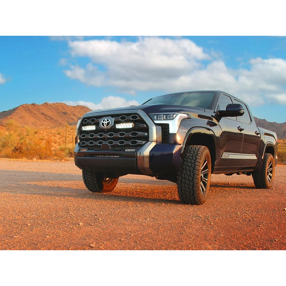 Toyota truck on a dirt road with mountains in the background with Lazer Lamps Grille Kit – Toyota Tundra Platinum (2022+)