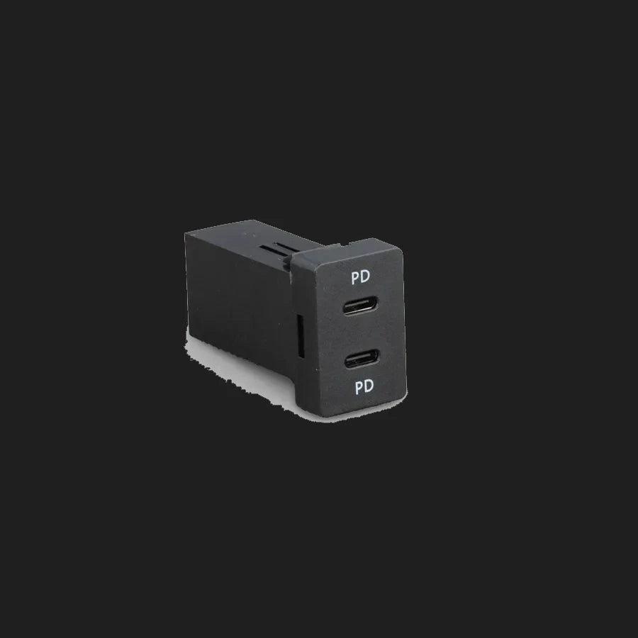 Toyota-fit dual USB-C charger at an angle, showing the depth of the body behind the panel and the two USB-C ports marked PD on the face