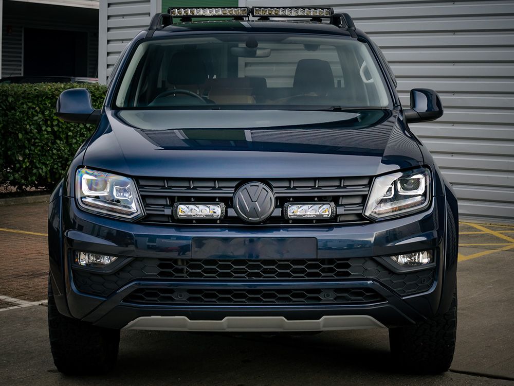 Front view of a black Volkswagen SUV with visible logo in a parking lot with Lazer Lamps Grille Kit for VW Amarok V6 (2016–2022)