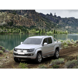 Silver Volkswagen Amarok parked on a dirt road with a scenic mountain and lake background
