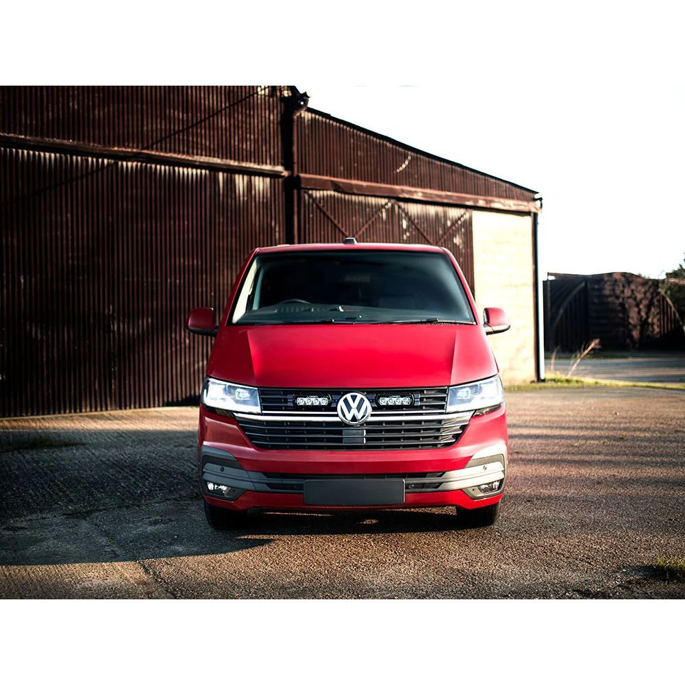 Red Volkswagen van parked in front of a rustic building.