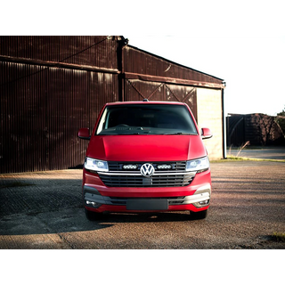 Red Volkswagen van parked in front of a rustic building.