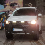 White Volkswagen van with headlights on in front of a colorful mural with Lazer Lamps Grille Kit for Volkswagen T5.1