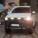 White Volkswagen van with headlights on in front of a colorful mural with Lazer Lamps Grille Kit for Volkswagen T5.1