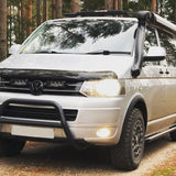 White van with roof rack and off-road bumper in a forest setting